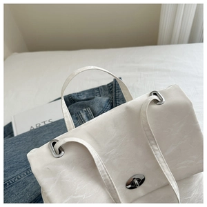 Detail of white wrinkled leather bag with metallic twist lock and silver chain strap