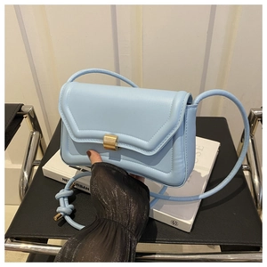 Close-up of light blue PU leather saddle bag with golden rectangular metal buckle closure