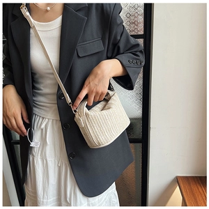 Detailed close-up of beige woven texture and herringbone pattern on the small crossbody bag