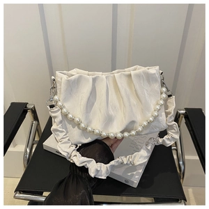Dettaglio della borsa a nuvola pieghettata crema con manico elegante in perle e cristalli
