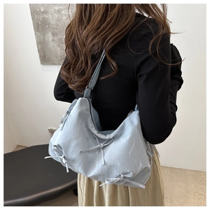 Close-up of light blue shoulder bag with bow details and textured marble pattern fabric