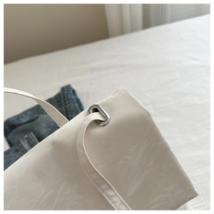 Detail of cream soft leather bag featuring marble texture and silver metal eyelets