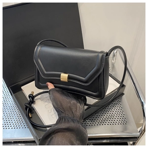 Detail of minimalist black saddle bag with gold metal buckle and knotted strap