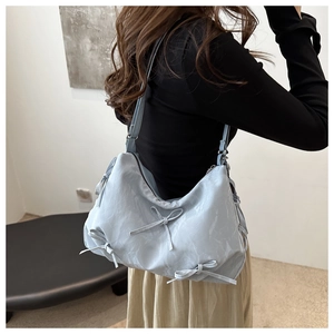 Detail of light blue shoulder tote bag with soft marble texture and ribbon bows