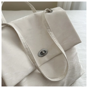 Close-up of cream leather shoulder bag texture with silver metal rotating buckle detail