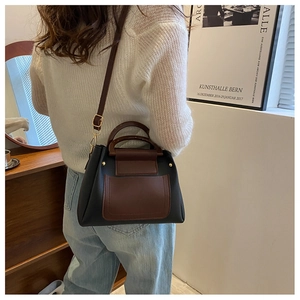Detail of a color-block crossbody bag with leather texture and golden metal rivets