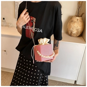 Detail of pink mini bucket bag featuring large pearl handle and gold chain strap