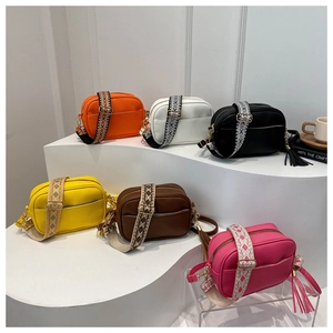 Close-up of litchi grain leather crossbody bags with patterned wide shoulder straps