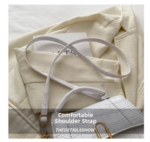 Detailed view of white crocodile pattern crossbody bag with gold metal buckle and strap