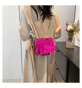 Detail view of fuchsia sequin crossbody bag with silver chain strap on model