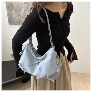 Détail du sac hobo bleu clair avec des nœuds décoratifs et du similicuir souple plissé