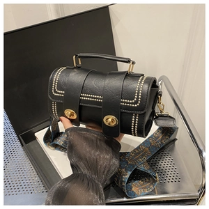 Detail of black Boston bag with gold studs and vintage pattern wide shoulder strap