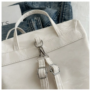 Detail of white wrinkled leather handle and silver metal buckles on a chain shoulder bag