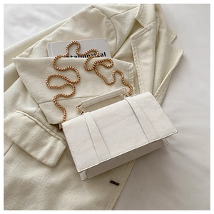 Detail of white PU leather rectangular crossbody bag with elegant gold chain strap