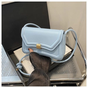 Close-up of light blue leather crossbody saddle bag with gold metal buckle detail
