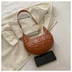 Detailed view of brown crescent shoulder bag with 3D geometric embossed texture and gold buckles