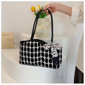 Detail of tweed checkered tote bag with polka dot silk scarf tied on the leather handle