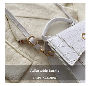 Detail of adjustable strap with gold buckle on white crocodile pattern leather handbag
