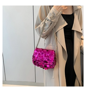 Detail of fuchsia sequin shoulder bag with silver chain strap on light beige coat