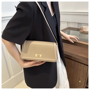 Detail of beige leather crossbody bag with golden twist lock on a minimalist flap square bag