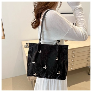 Detail of a large black tote bag featuring exquisite white butterfly appliques and texture