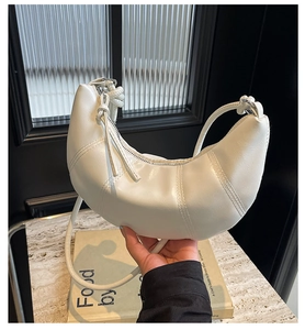Close-up of white PU leather crescent bag with curved stitching and top zipper