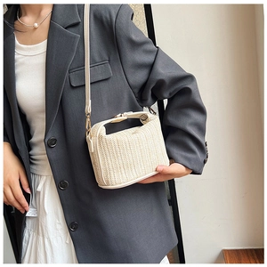 Detail of cream straw crossbody bag with PU trim and gold hardware on a gray blazer