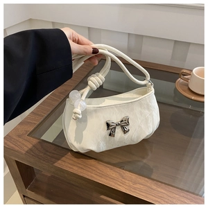 Close-up of beige pleated handbag featuring silver butterfly buckle and bead details