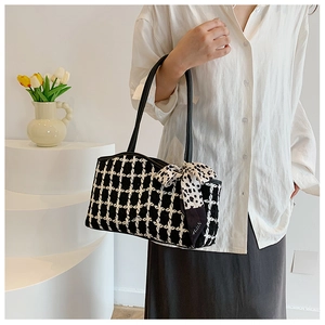 Detail of tweed checkered tote bag with black strap and polka dot decorative scarf