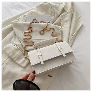 Detail of white textured leather crossbody bag with gold chain strap on blazer