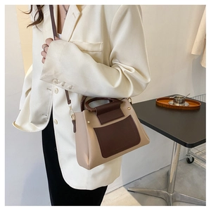 Detail of a vintage two-tone shoulder bag featuring wooden handles and beige PU leather