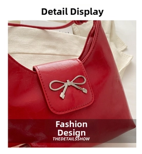 Close-up of bright red glossy leather handbag featuring a silver metallic bow detail