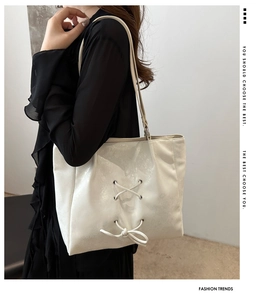 Detail of cream tote bag with stylish lace-up bows shown on model's shoulder