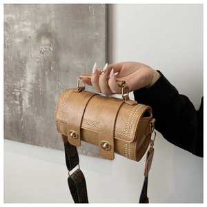 Detail of tan cylinder bag with gold rivets and vintage metallic twist-lock fasteners