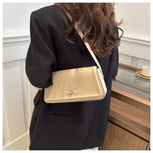 Detail of a minimalist cream shoulder bag featuring an elegant gold square twist lock clasp