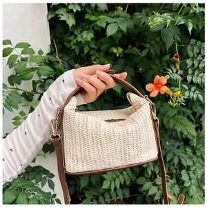 Detailed close-up of straw woven handbag with leather trim held in a garden setting