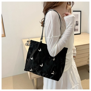 Close-up of a black bucket bag with silver butterfly charms and pleated nylon texture