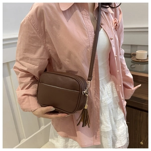 Dettaglio di una borsa a tracolla in pelle martellata marrone con frange decorative