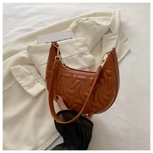 Detail view of brown crescent shoulder bag with geometric embossed leather and gold zipper