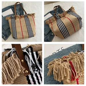 Detalle del bolso tote tejido con detalles de flecos y rayas sobre textura de paja