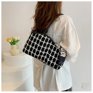 Detail of tweed checkered tote bag with black and white polka dot scarf and leather handles