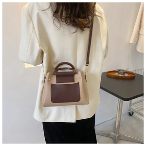Detail of color-block leather tote bag showing wood-texture handle and adjustable strap