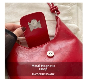 Detail view of the silver magnetic buckle on a red glossy leather bow bag interior