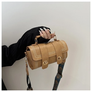 Detail of vintage brown cylinder bag featuring white stitching and colorful ethnic strap