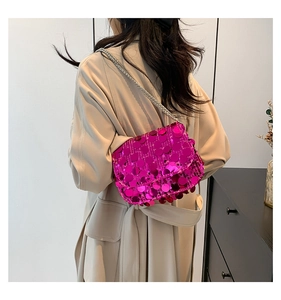 Detail of sequined crossbody bag in hot pink with elegant silver chain strap shown on model