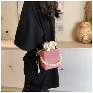 Détail du sac seau à rayures roses avec anse en perles, chaîne dorée et cordon de serrage