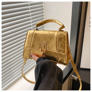 Close-up of golden crocodile pattern leather handbag with metallic U-shaped lock detail