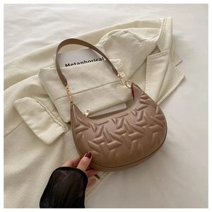 Detail view of caramel brown crescent shoulder bag with geometric embossed texture