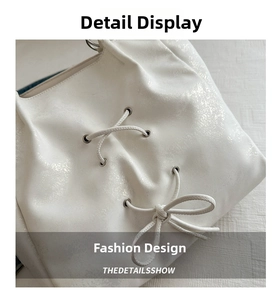 Detail of white bow tote bag featuring metallic grommets and pearlescent leather texture