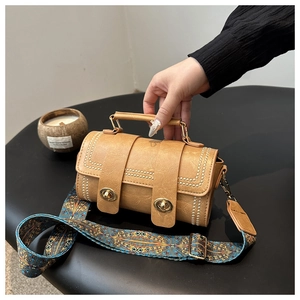 Detail of vintage cylindrical bag with metal studs, turn-locks and ethnic pattern strap